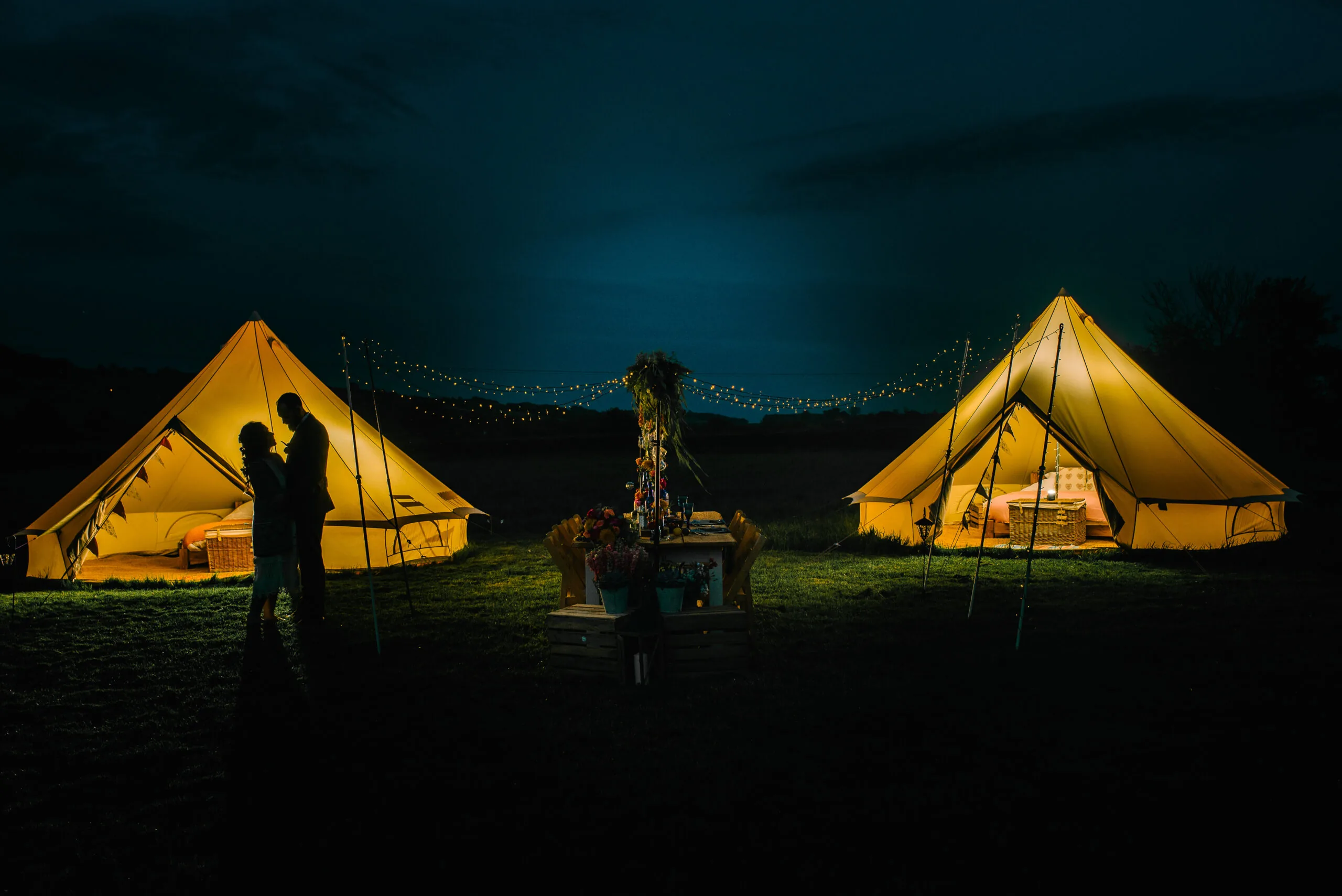 Bell tents lit up at night with fairy lights
